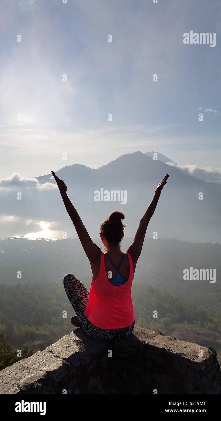 Young woman doing meditation at the sunrise sitting at the cliff in Bali, conscious living Stock Photo