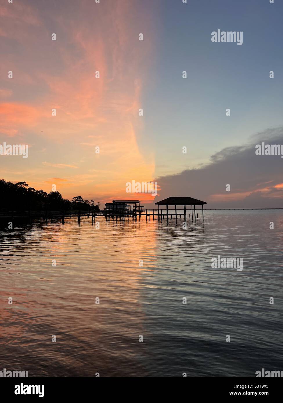 Divided sunset skies over bay water Stock Photo - Alamy