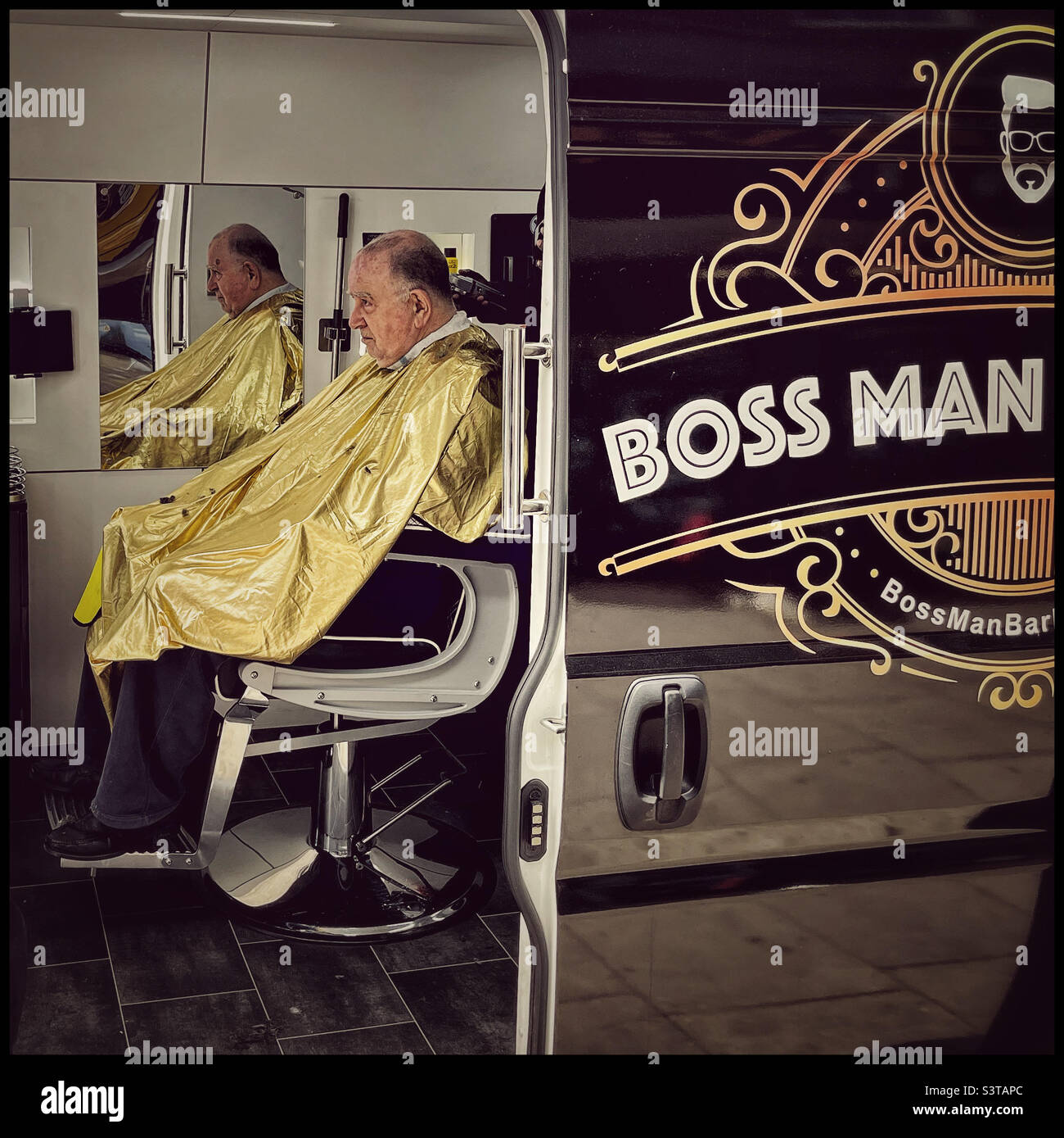 Elderly man having haircut in Boss Man mobile barber van Stock Photo