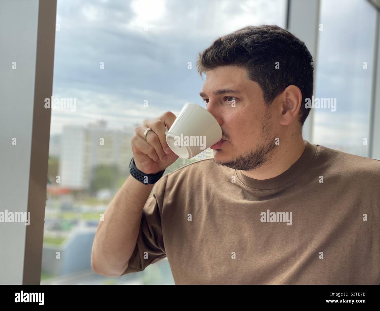 young man drinking coffee in a cafe near the panoramic window - Smartphone Captured Stock Image