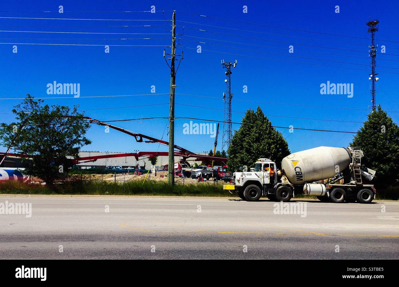 A concrete-mixer truck on the road outside a modern construction site in an urban area, Ontario, Canada. Build back better. - Smartphone Captured Stock Image