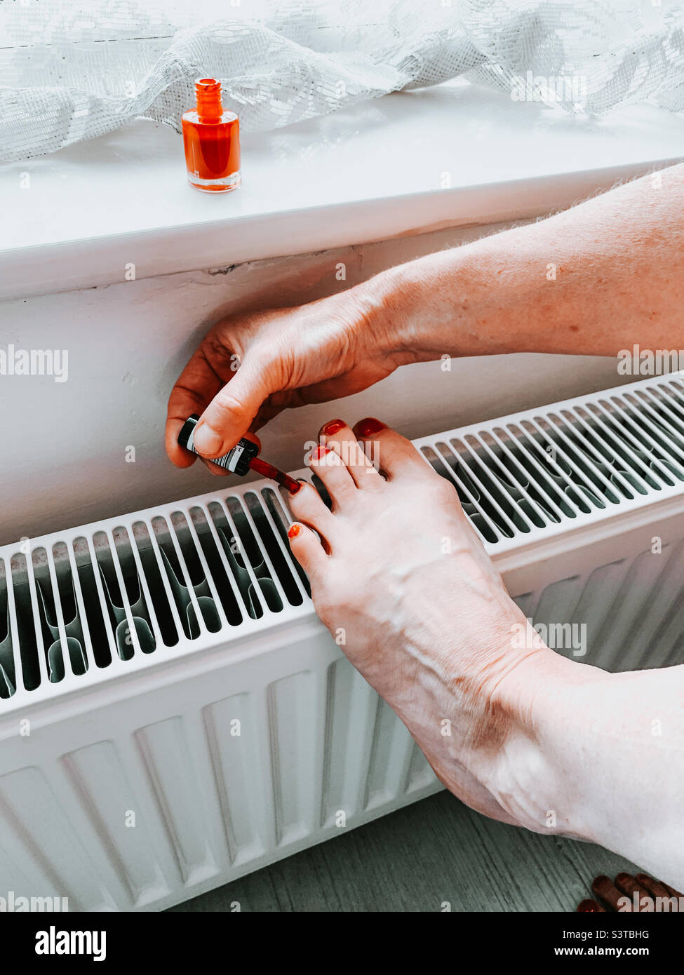 Woman painting her toenails red - Smartphone Captured Stock Image