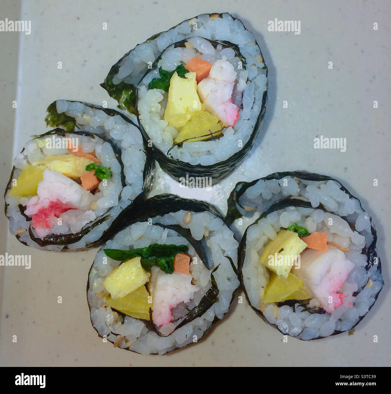 Kimbap is a Korean dish made from cooked rice and ingredients such as vegetables, fish, and meats that are rolled in gim—dried sheets of seaweed—and served in slices. Stock Photo