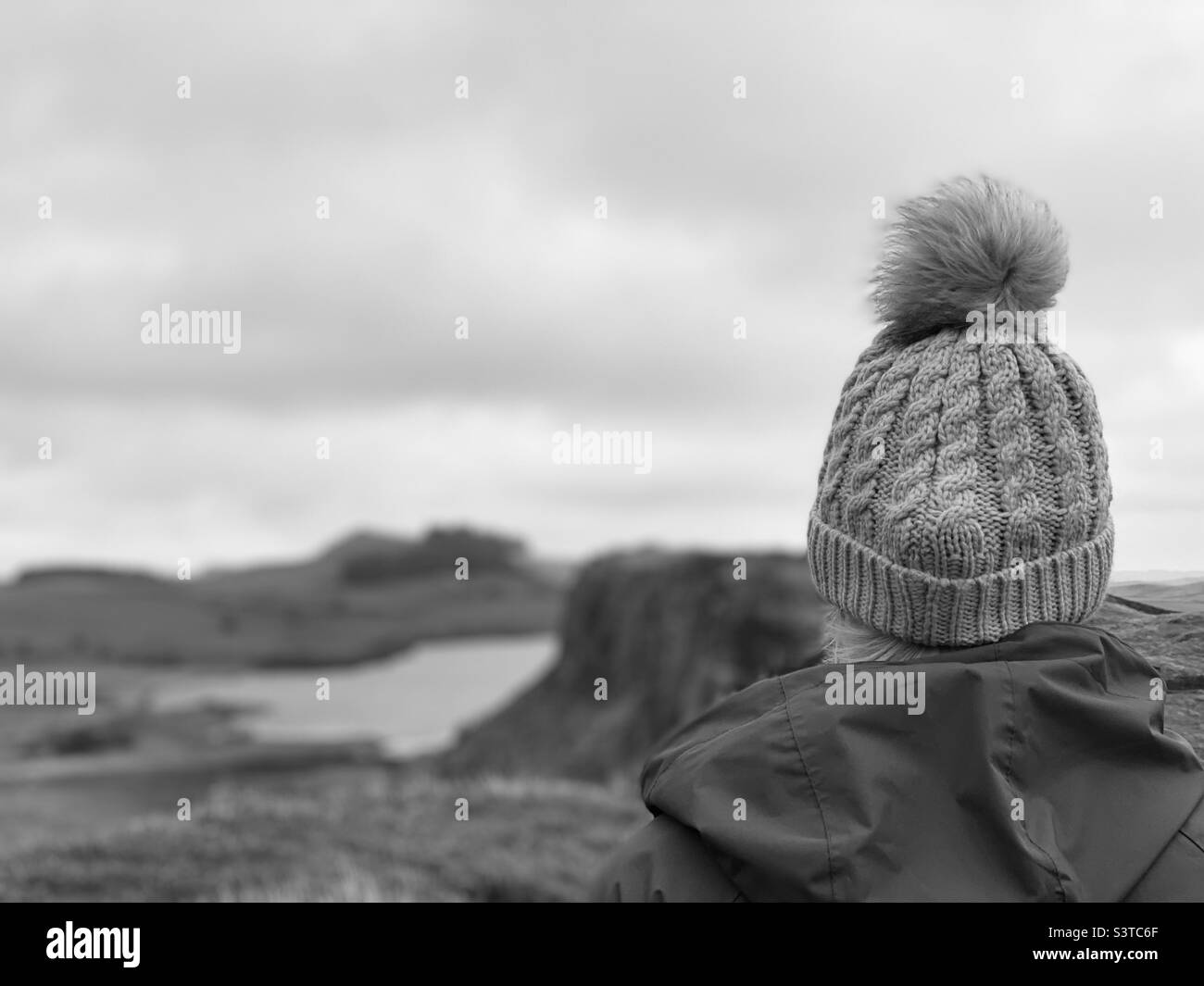 Rear view of woman wearing a knit hat walking in the countryside Stock Photo