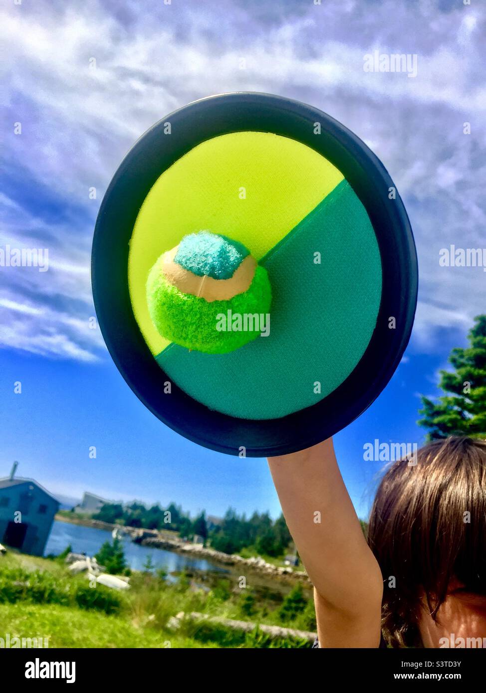 Outdoor fun. Kids’ game by the sea. Raise your arm, snap the ball. Detach, throw, repeat - Smartphone Captured Stock Image