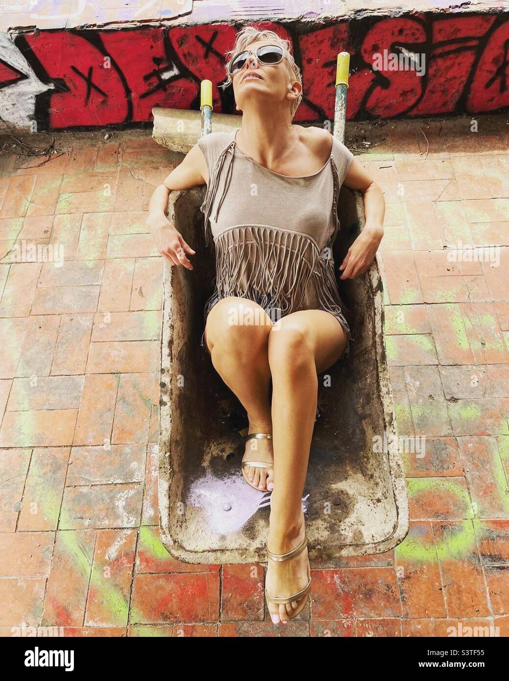 Woman lying in a wheelbarrow Stock Photo