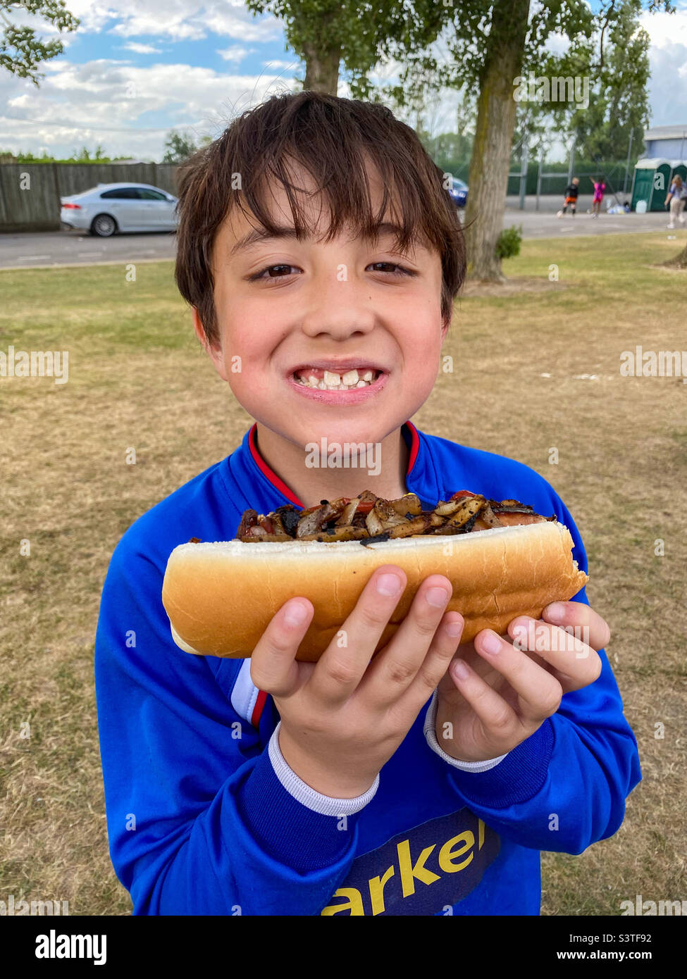 A boy happy to have. A hotdog to eat at the end of his football tournament. - Smartphone Captured Stock Image