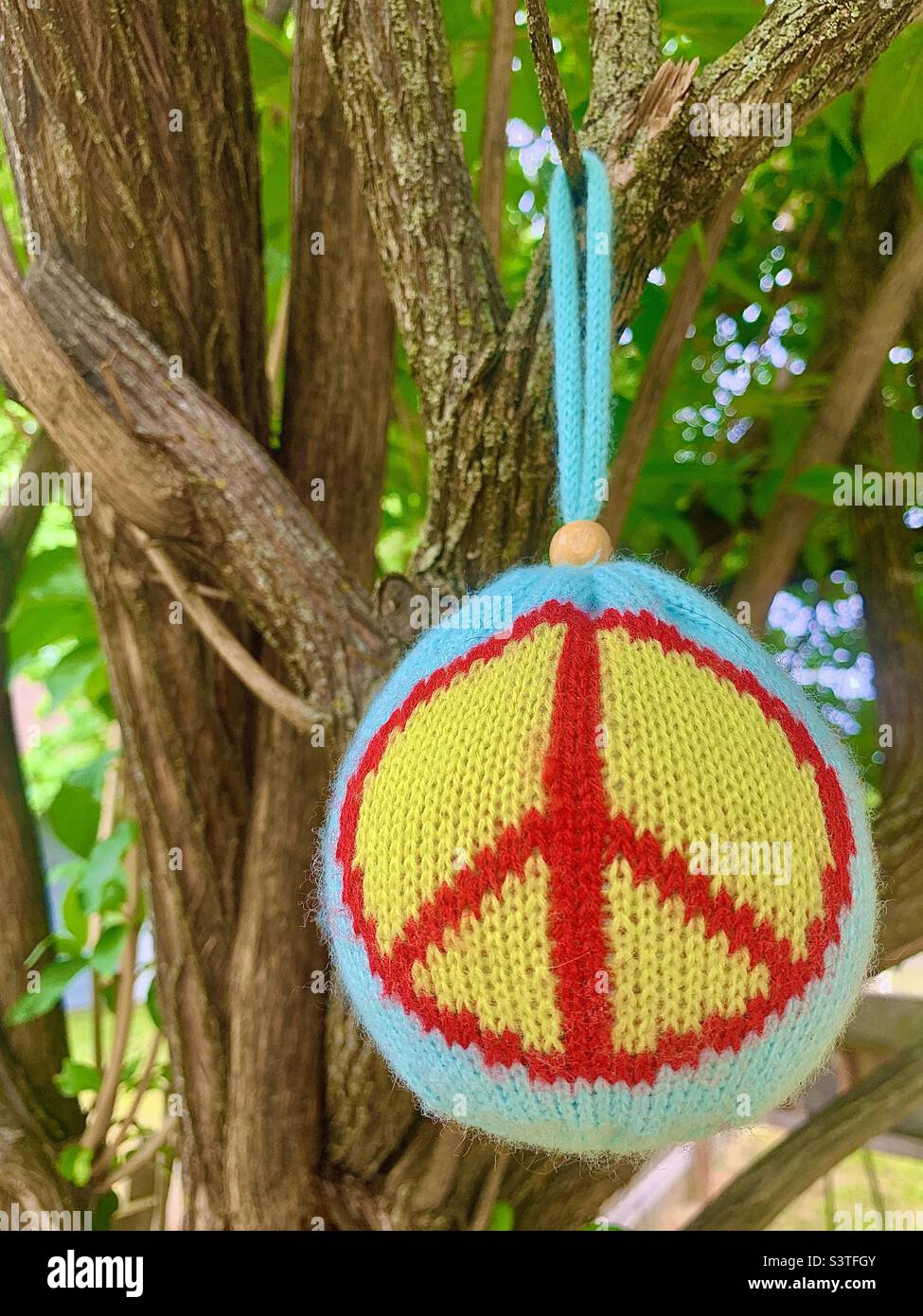 Textured peace symbol ornament hanging from outside tree Stock Photo