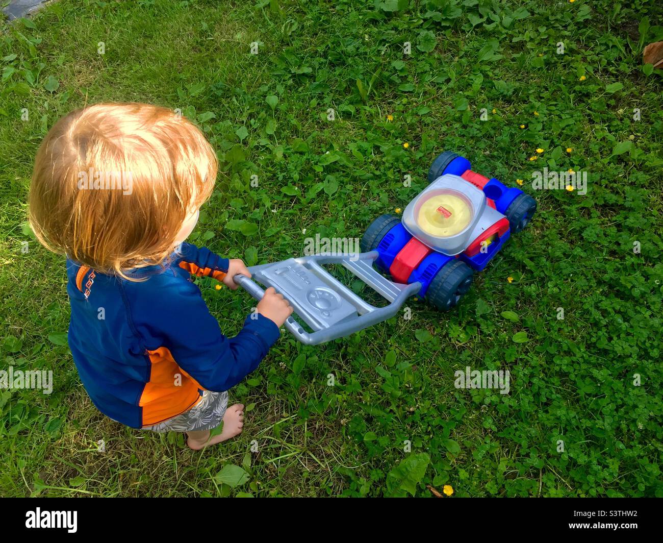 Little gardening help. Toddler with a toy lawnmower. Right sounds, no function. Halifax, Canada - Smartphone Captured Stock Image