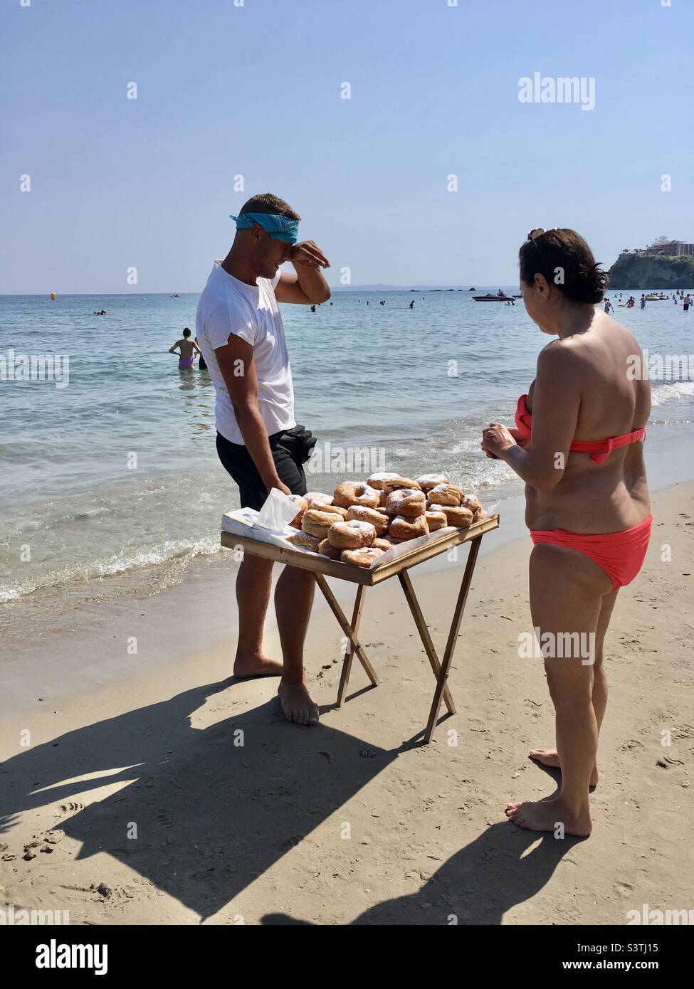 Man selling doughnuts on a beach in Greece Stock Photo