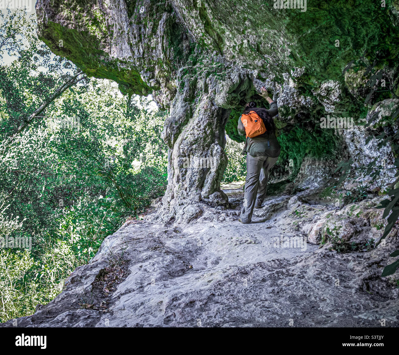 Female hikers passes under a natural archway in the cliff face - Smartphone Captured Stock Image