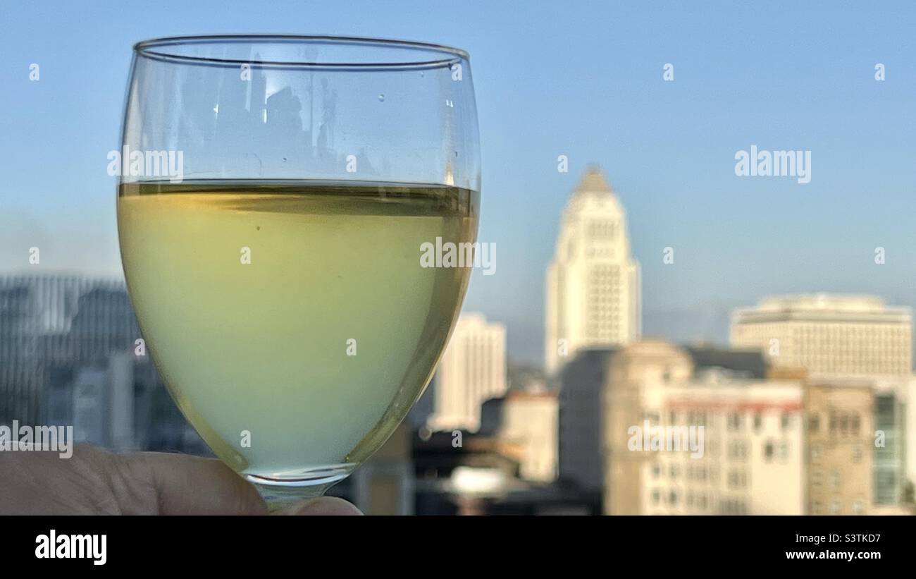 Glass of white wine with Los Angeles Downtown skyline, soft focus in background - Smartphone Captured Stock Image