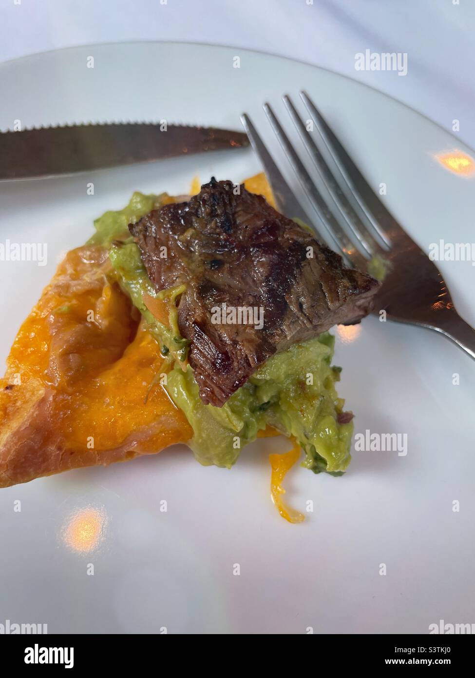 Close up of a single steak nacho appetizer on a white plate with a knife and fork, 2022, USA - Smartphone Captured Stock Image Close up of a single steak nacho appetizer on a white plate with a knife and fork, 2022, USA - Smartphone Captured Stock Image