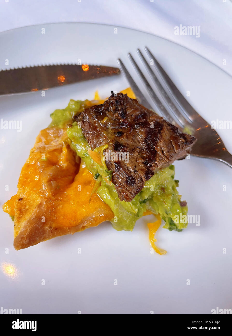 Close up of a single steak nacho on a white plate with a dinner fork at a Mexican restaurant in New York City, 2022, USA Stock Photo