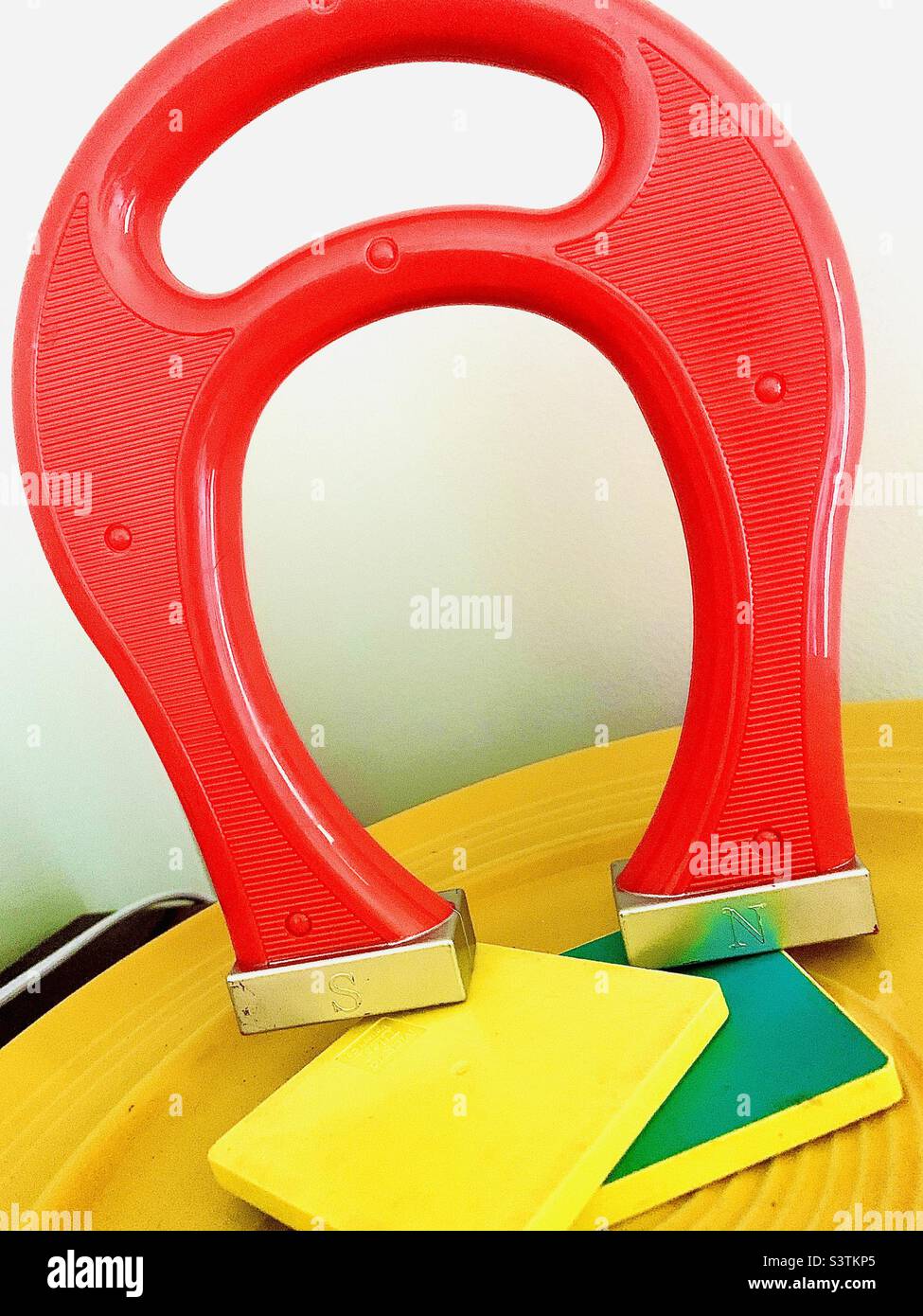 Oversized red horseshoe magnet on yellow tray Stock Photo