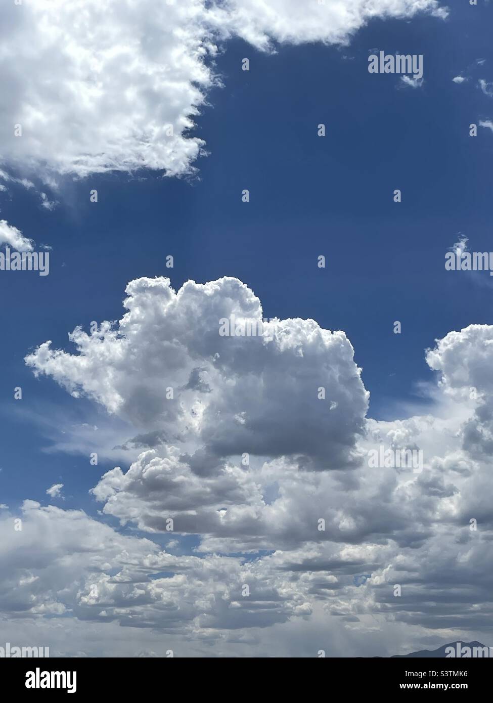 Beautiful cumulus clouds decorate the skies over the Salt Lake valley in Utah, USA in July on a nice summer day. - Smartphone Captured Stock Image