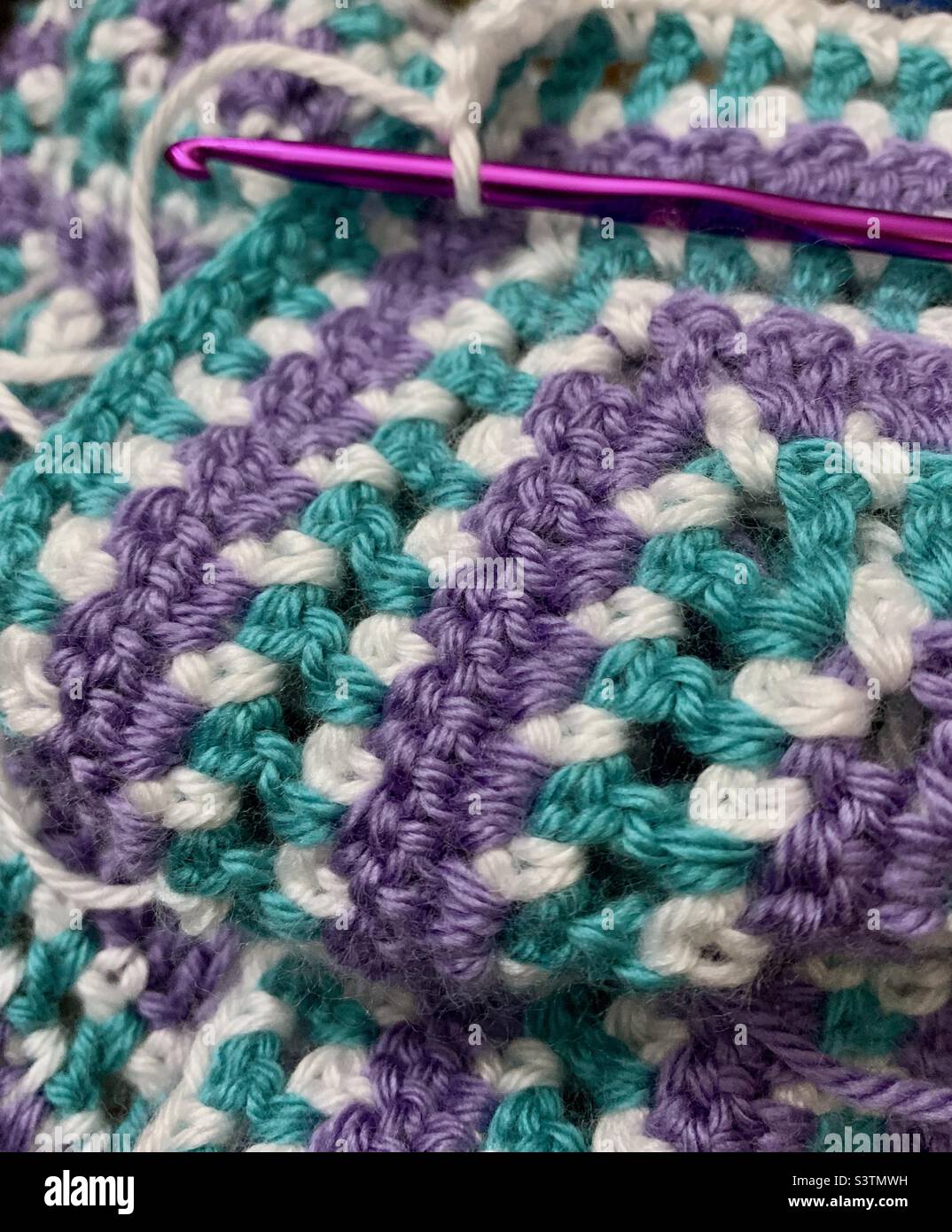 Close-up of purple aluminum crochet hook and crocheted blanket Stock Photo