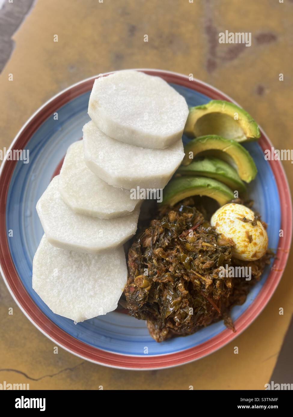 Local food in Ghana; boiled yam with cocoyam leafs stew, boiled egg and