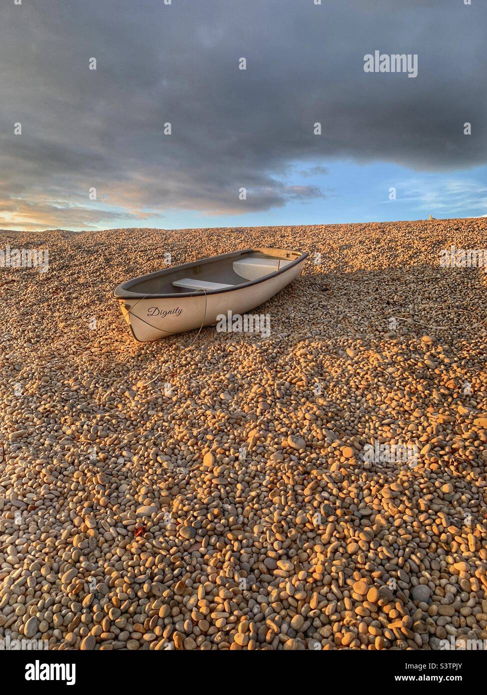 Small boat on a bank of pebbles at Chesil beach - Smartphone Captured Stock Image