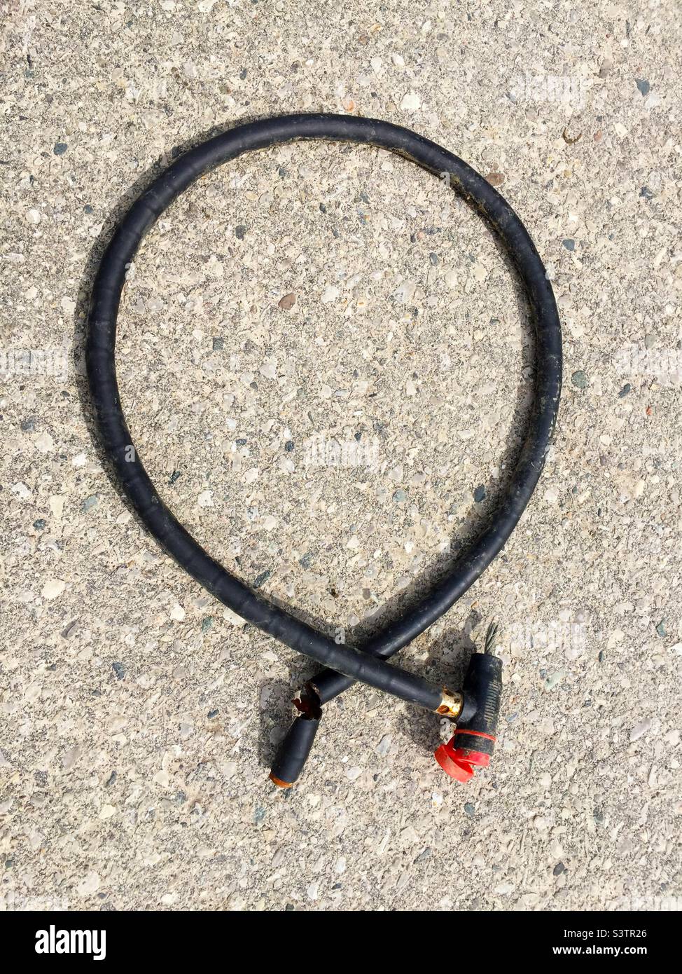 Cut lock cable, after a bike was stolen, Ontario, Canada. Left behind on the pavement. Not very secure lock. - Smartphone Captured Stock Image