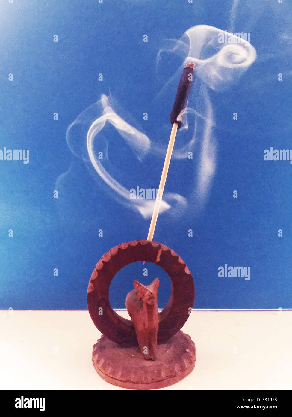 Swirling incense smoke against a sky-blue backdrop. Animal spirit. - Smartphone Captured Stock Image