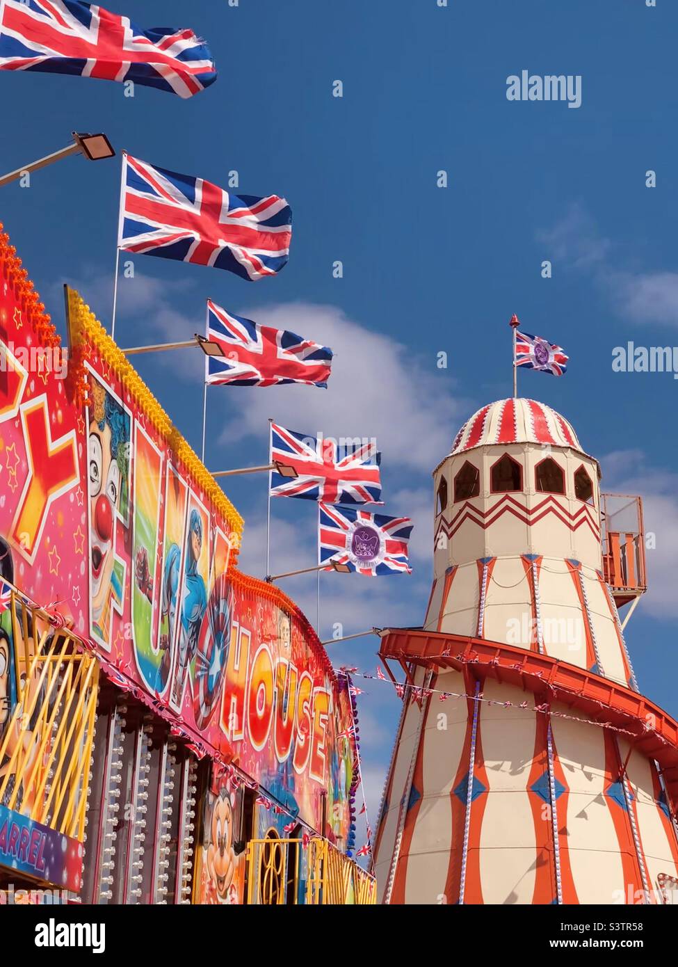 British summer seaside funfair amusement park with Union Jack Flags flying in a blue sky - helter skelter summertime Britain UK - Smartphone Captured Stock Image British summer seaside funfair amusement park with Union Jack Flags flying in a blue sky - helter skelter summertime Britain UK - Smartphone Captured Stock Image