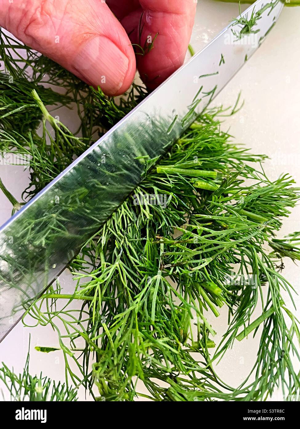 Man chopping fresh dill on a cutting board, USA - Smartphone Captured Stock Image