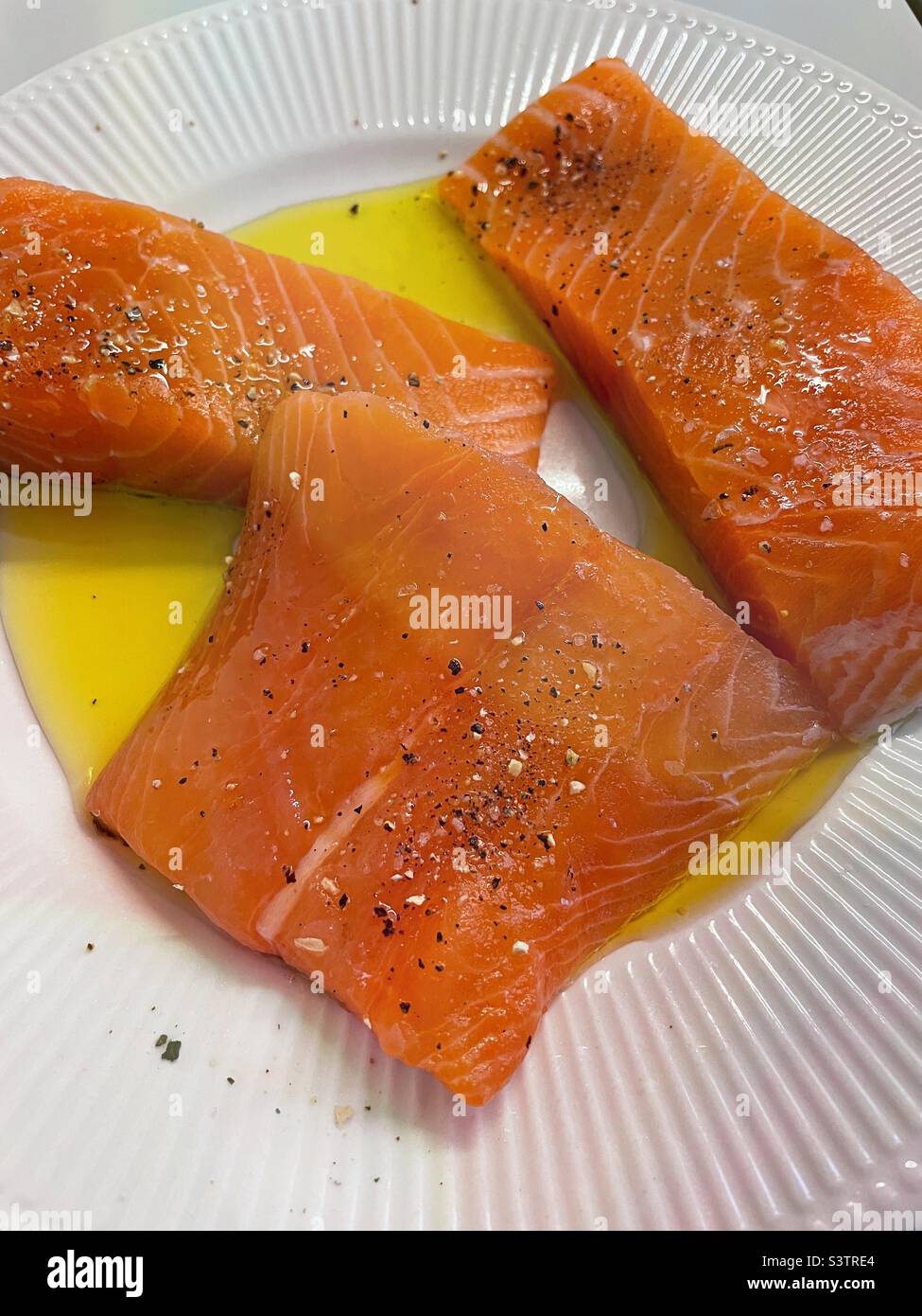 Three fresh salmon fillets spiced and boiled on a prep plate in a residential kitchen, 2022, USA - Smartphone Captured Stock Image