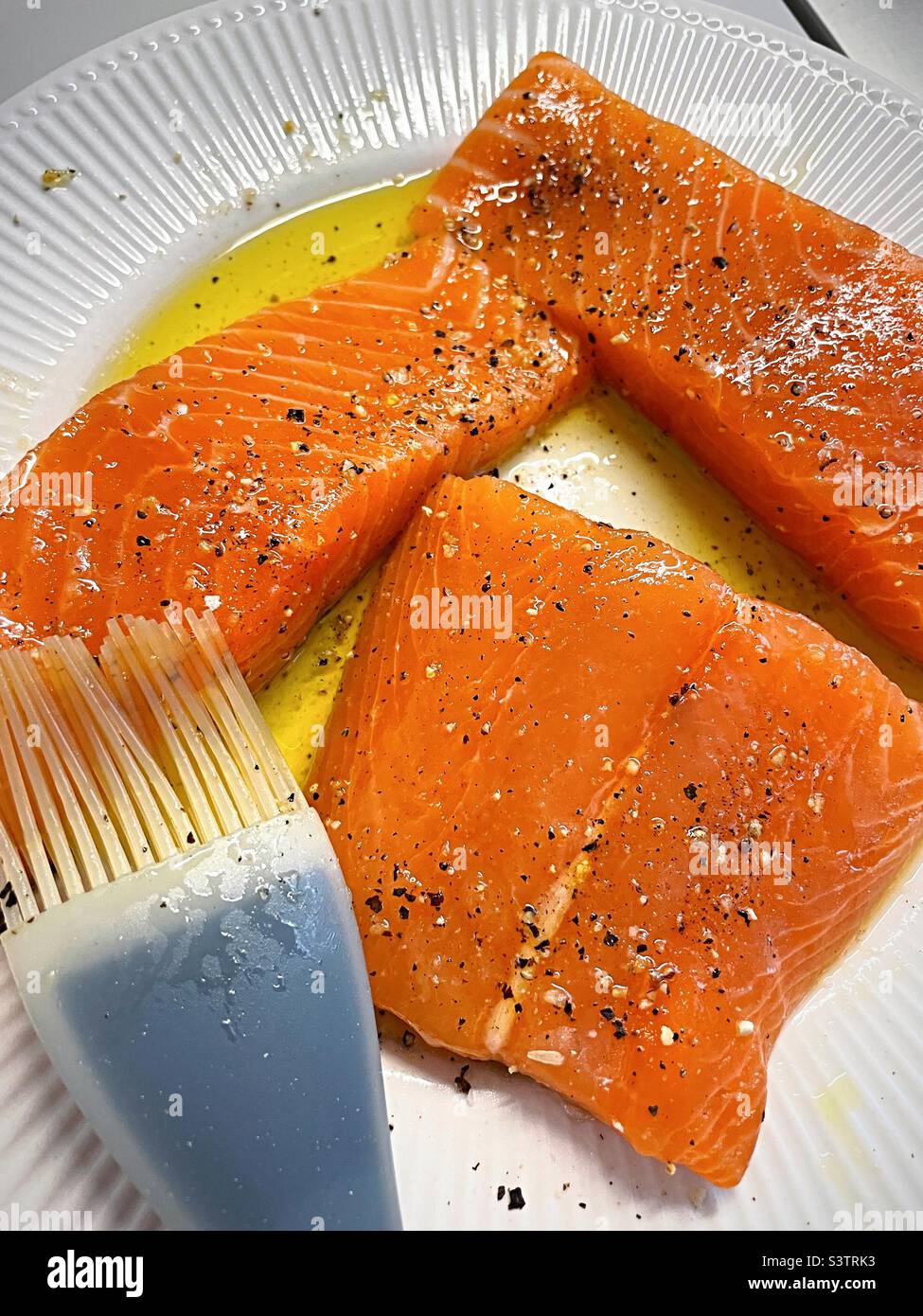 Close-up of fresh salmon fillets being brushed with olive oil in preparation for grilling, 2022, USA - Smartphone Captured Stock Image