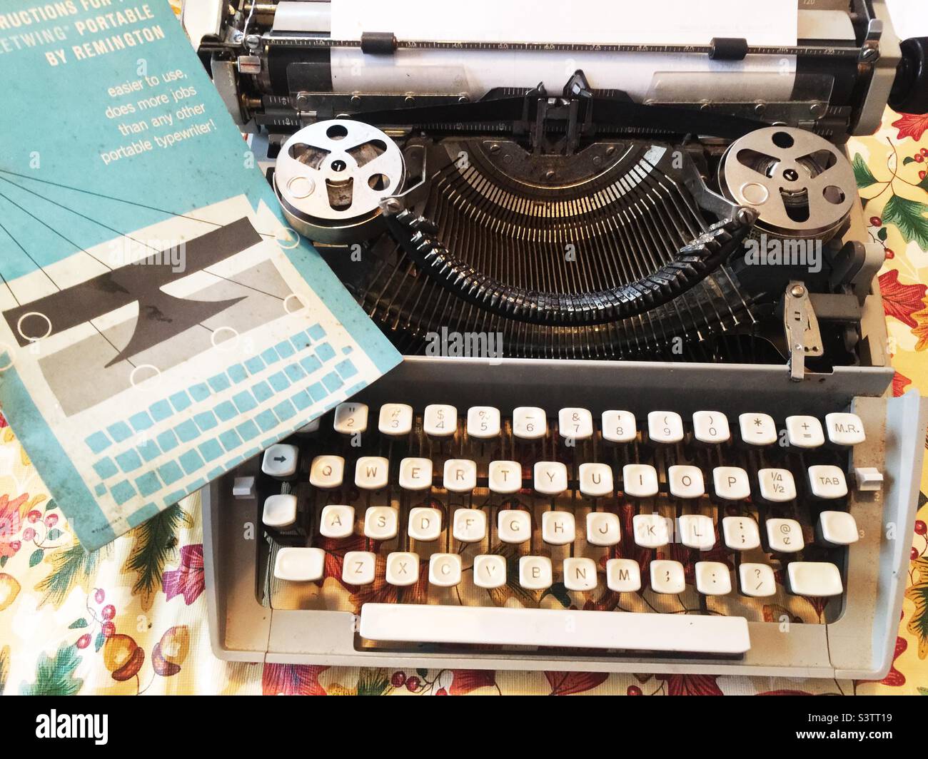 Vintage manual typewriter with instruction manual. Shows keys, type, ribbon spools. Stock Photo