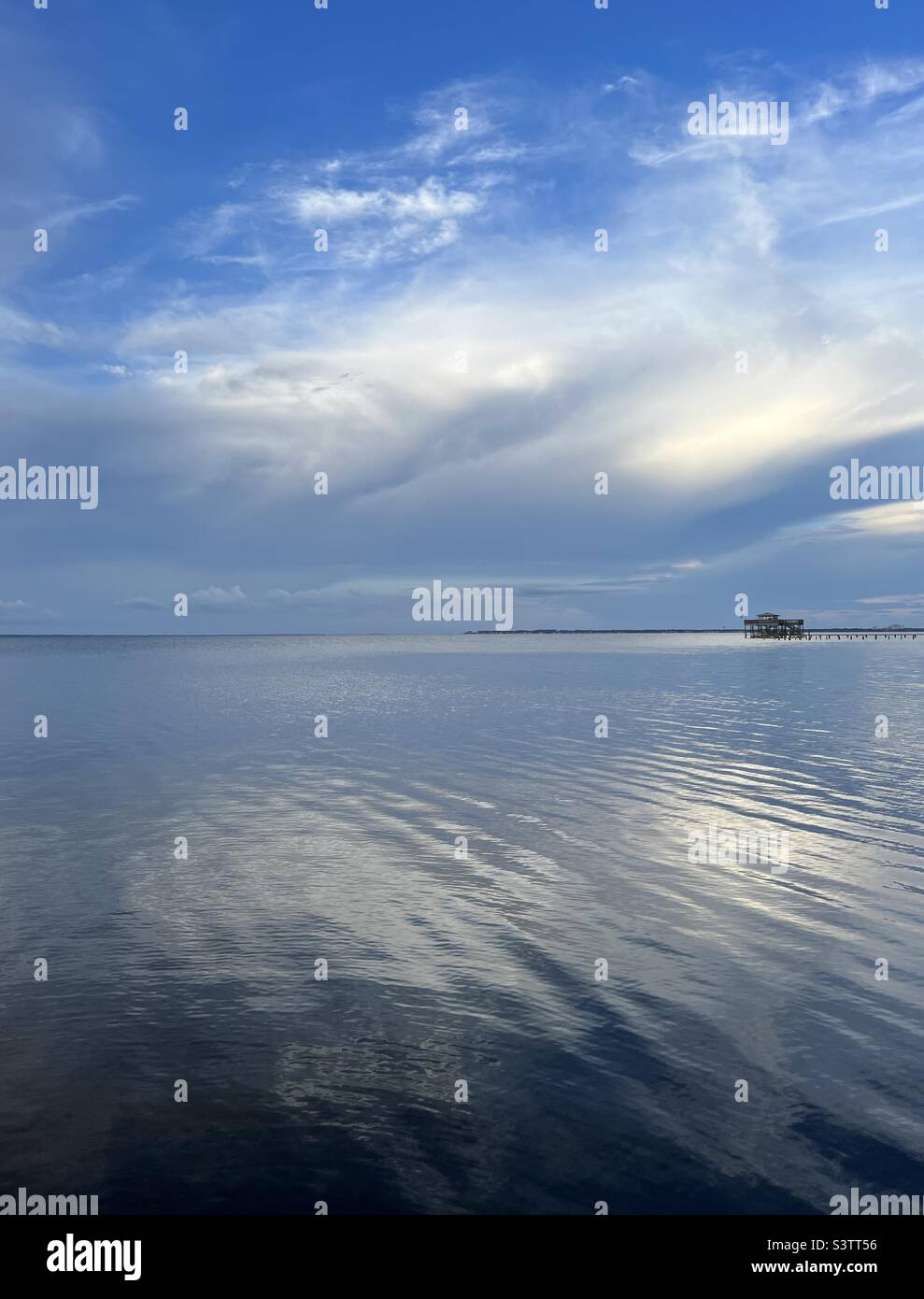 Sun reflecting into white clouds with reflections onto water Stock Photo