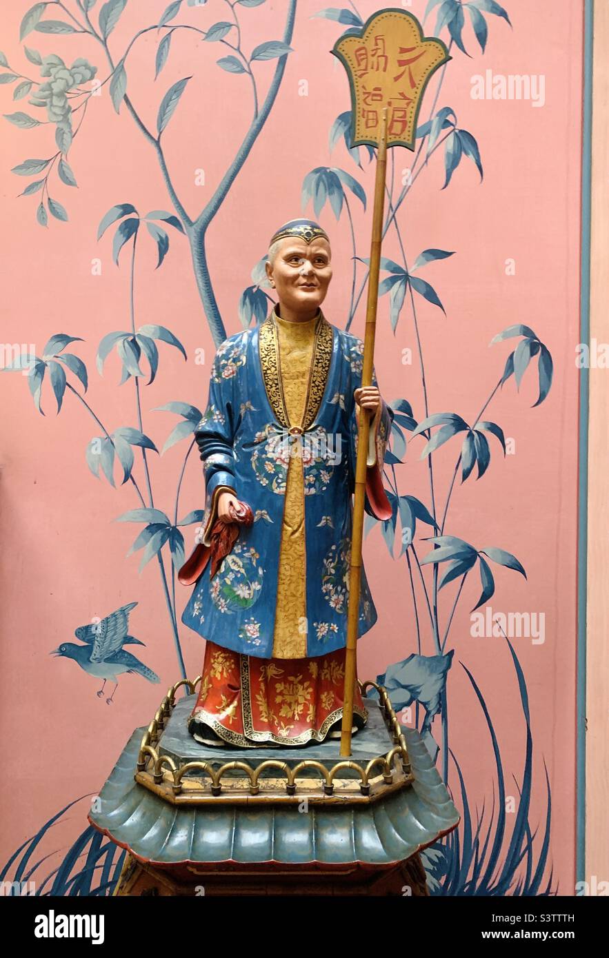 Chinese man ornament with pink chinoiserie wallpaper background at Brighton pavilion - Smartphone Captured Stock Image