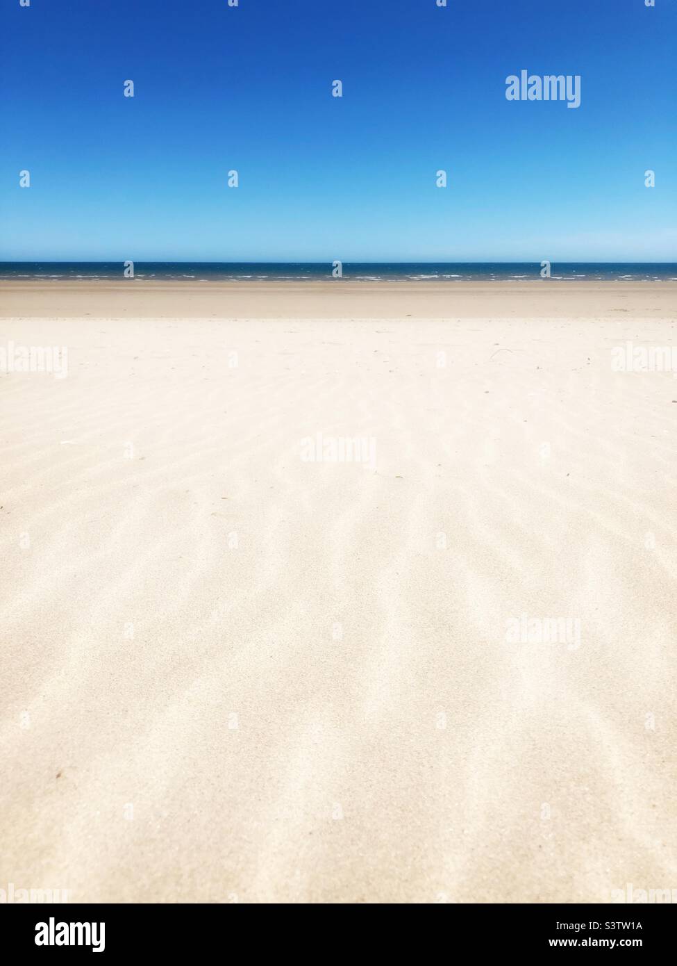 Travel and summer vacation background of the rippled sand on a white sandy beach and with blue sky and copy space Stock Photo