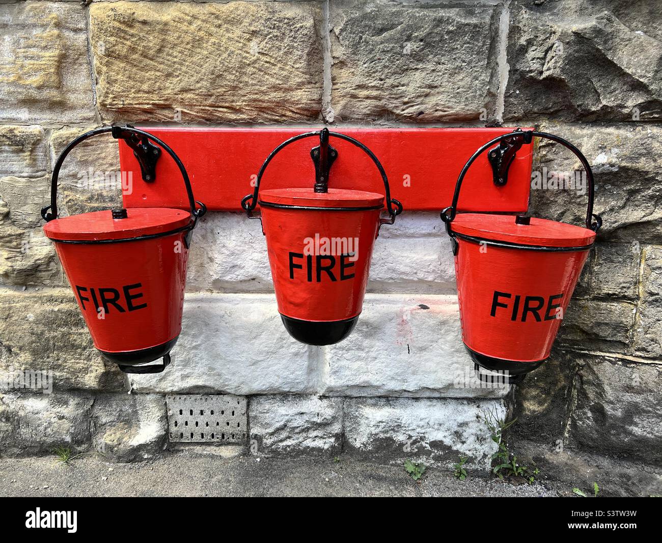 Three red fire buckets at a railway station Stock Photo