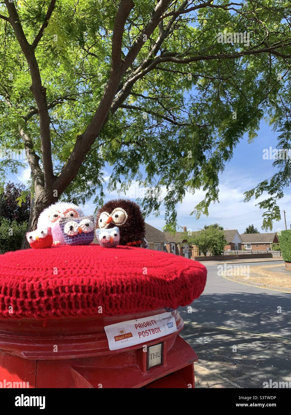 Kesgrave, Suffolk, UK - 14 July 2022: Priority postbox with a woollen knitted owl family topper. - Smartphone Captured Stock Image