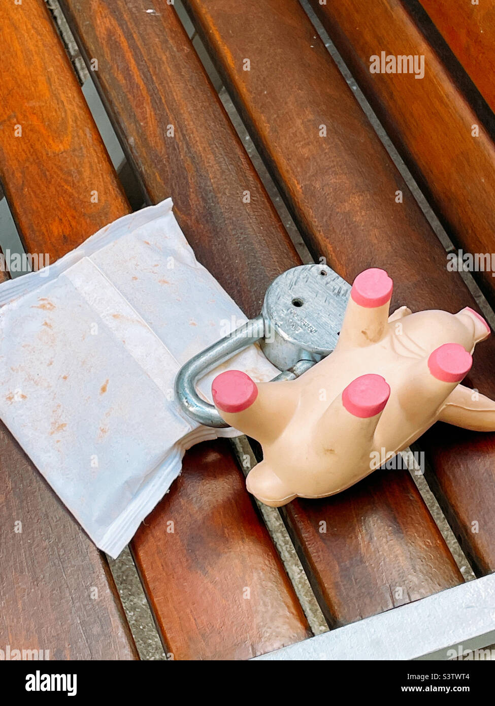 Discarded small plastic pig and a combination lock on a New York City park bench, 2022, NYC, USA Stock Photo