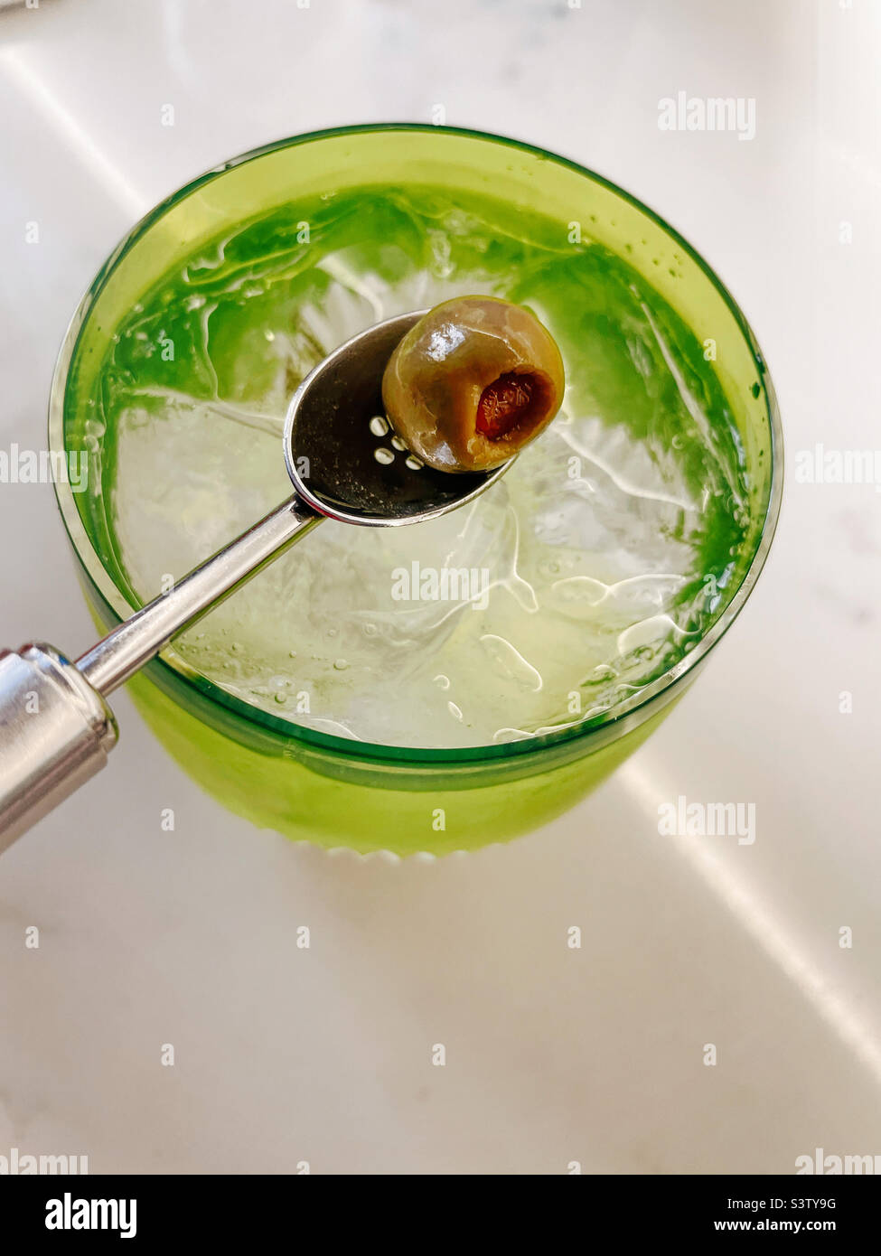 Close-up of all of spoon delivering an olive to a vodka martini on the rocks in a crystal glass, 2022, USA Stock Photo