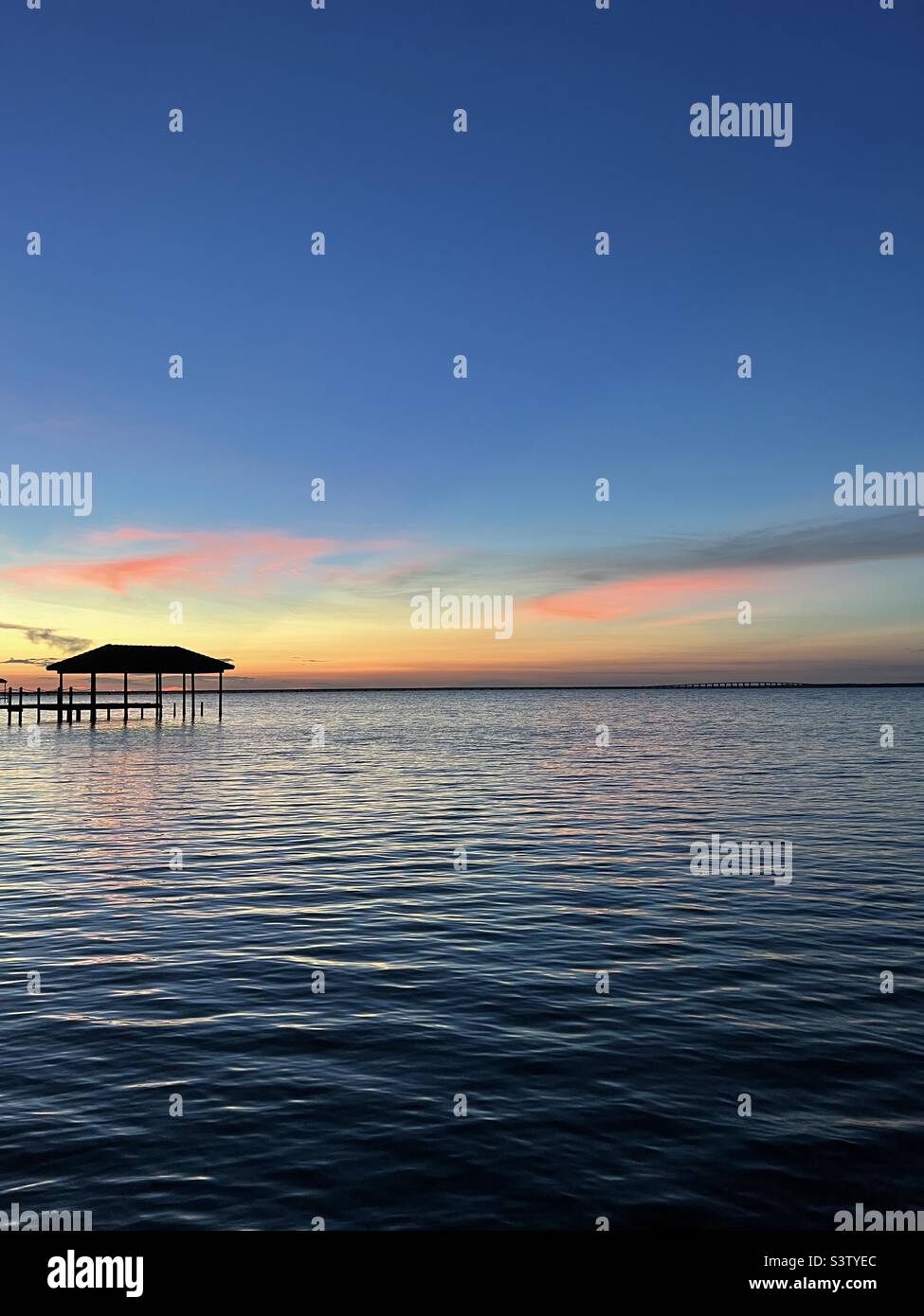 Colorful blue hour sunset with pier over bay water Stock Photo