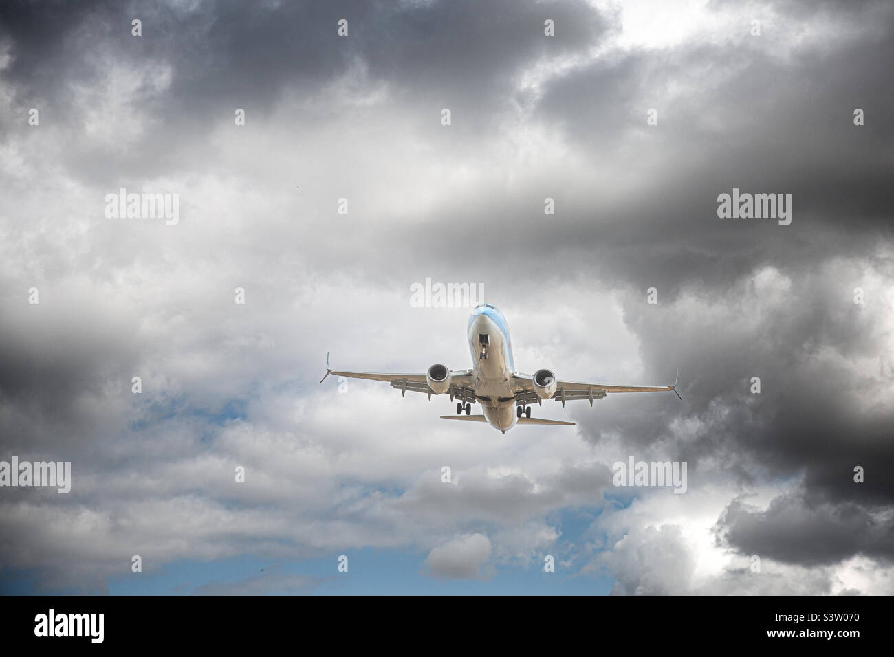 A passenger plane taking off or landing and flying through turbulence with dark clouds in a travel issues concept - Smartphone Captured Stock Image