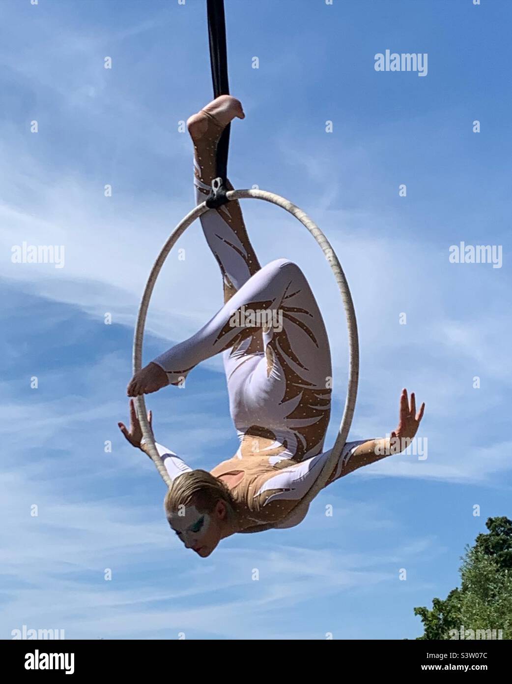 Female acrobat on suspended hula hoop in the park Stock Photo
