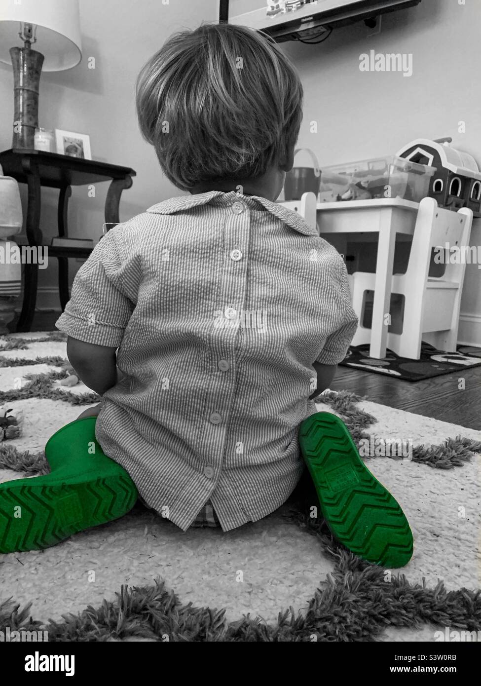 Little boy sitting in his dress shirt and favorite rain boots Stock Photo