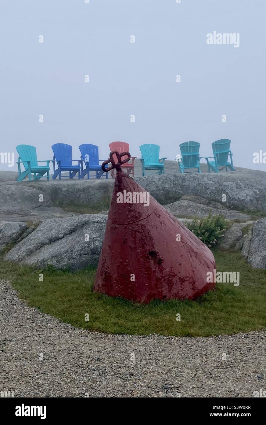 Retired buoy marker set in front of Muskoka chairs near the Peggy’s Cove lighthouse. - Smartphone Captured Stock Image