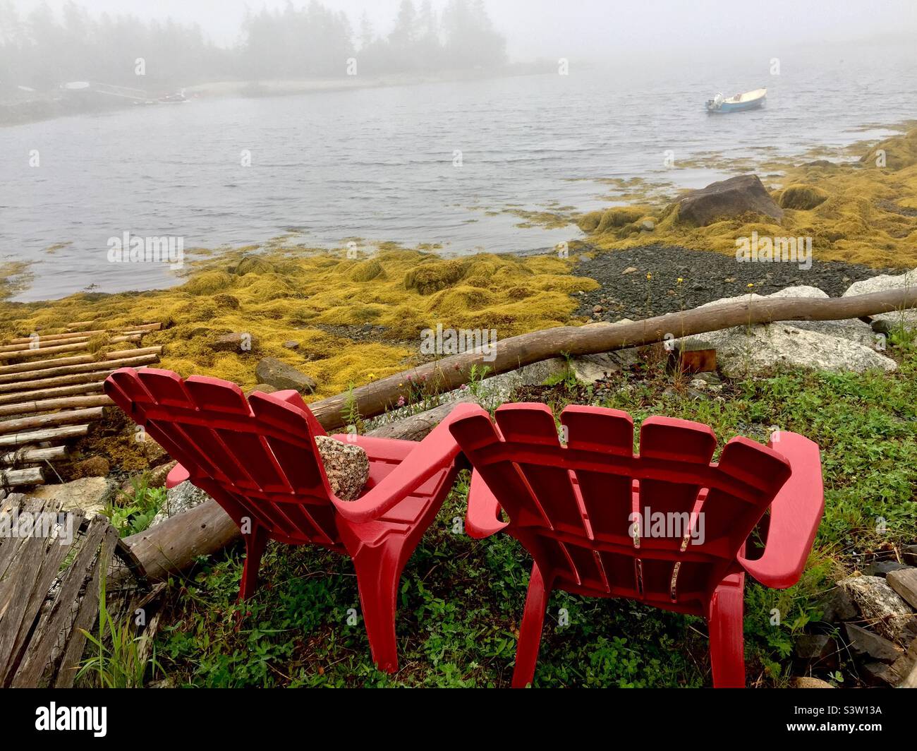 Waiting for fog to lift in a cove of the Atlantic Ocean, Halifax, Canada. Two unoccupied Adirondack chairs. Stock Photo