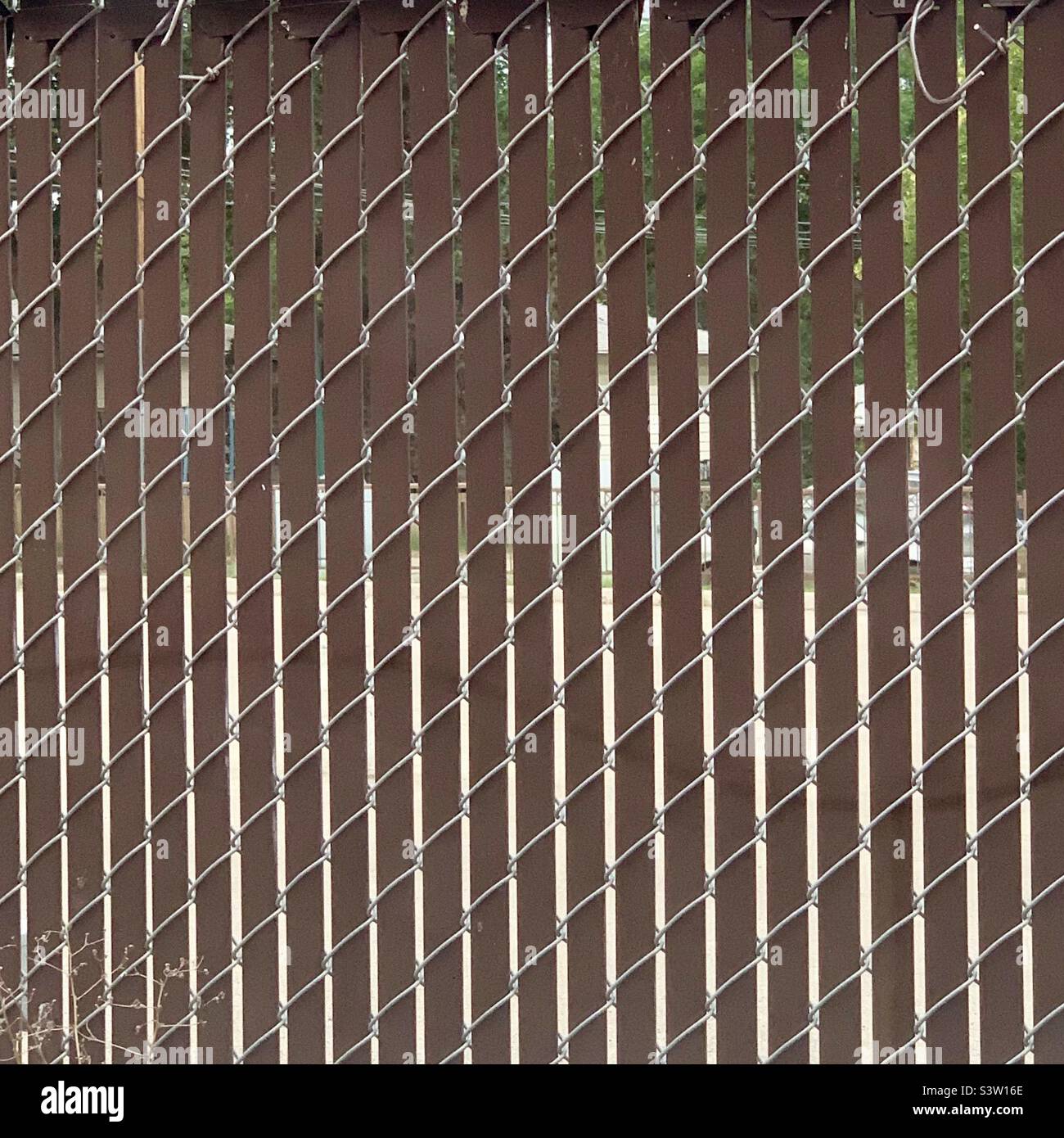 Chain link fence with PVC slats forming zigzag pattern - Smartphone Captured Stock Image