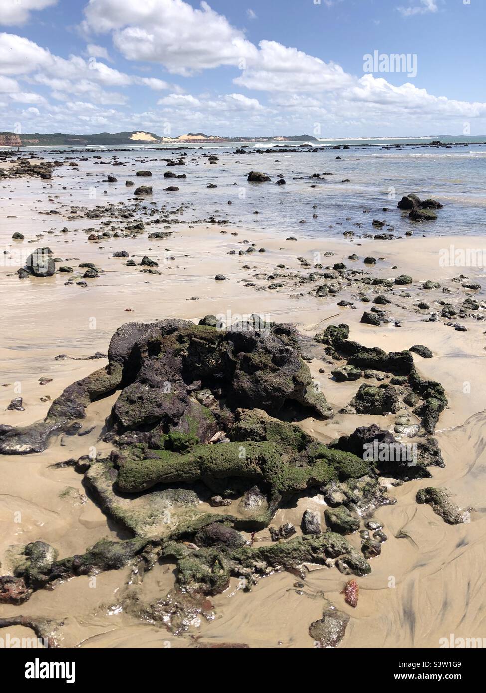 Low tide reveals rocks on the beach. Stock Photo