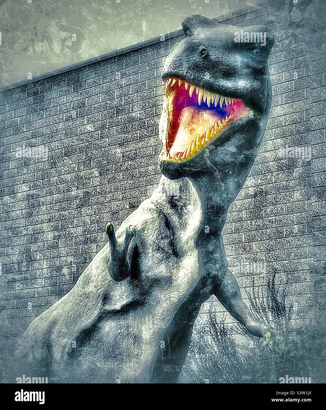 A large T-Rex sculpture in the outdoor courtyard of the Dinosaur Museum in Vernal, Utah, USA. Color and grunge effects are digitally added. - Smartphone Captured Stock Image