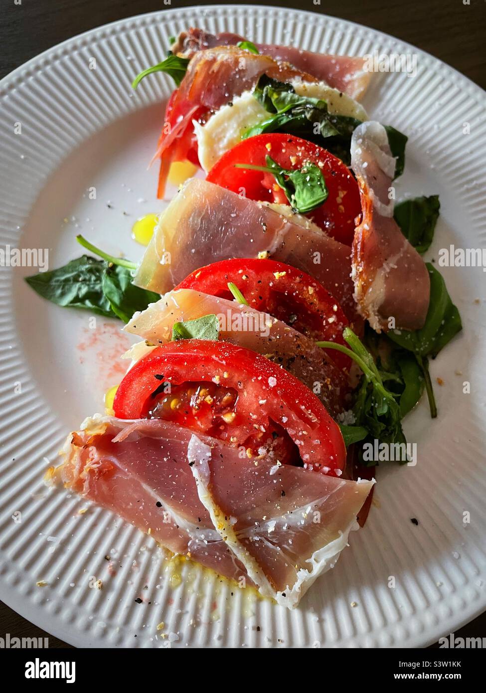 Close up of a main course Italian salad of prosciutto, vine ripe and tomato, mozzarella cheese and basil, 2022, USA Stock Photo