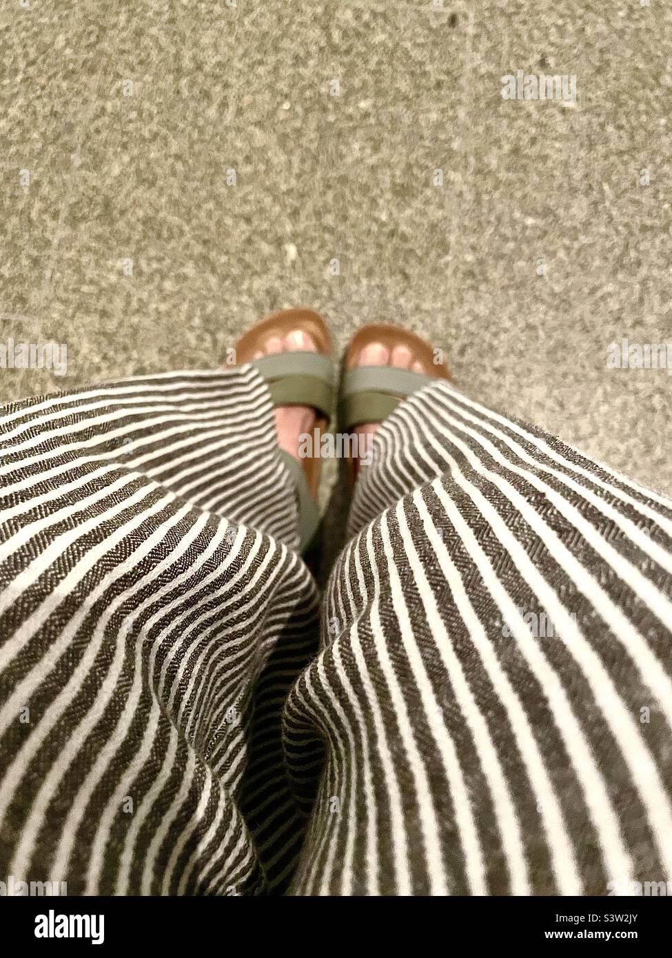 Downward view of striped pants & sandals - Smartphone Captured Stock Image