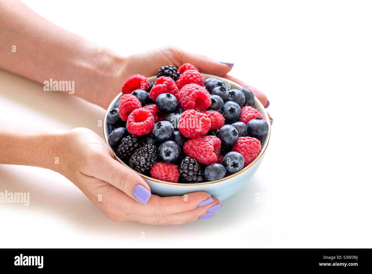 Healthy summer snack. Bowl of freshly picked berries in hands. Stock Photo