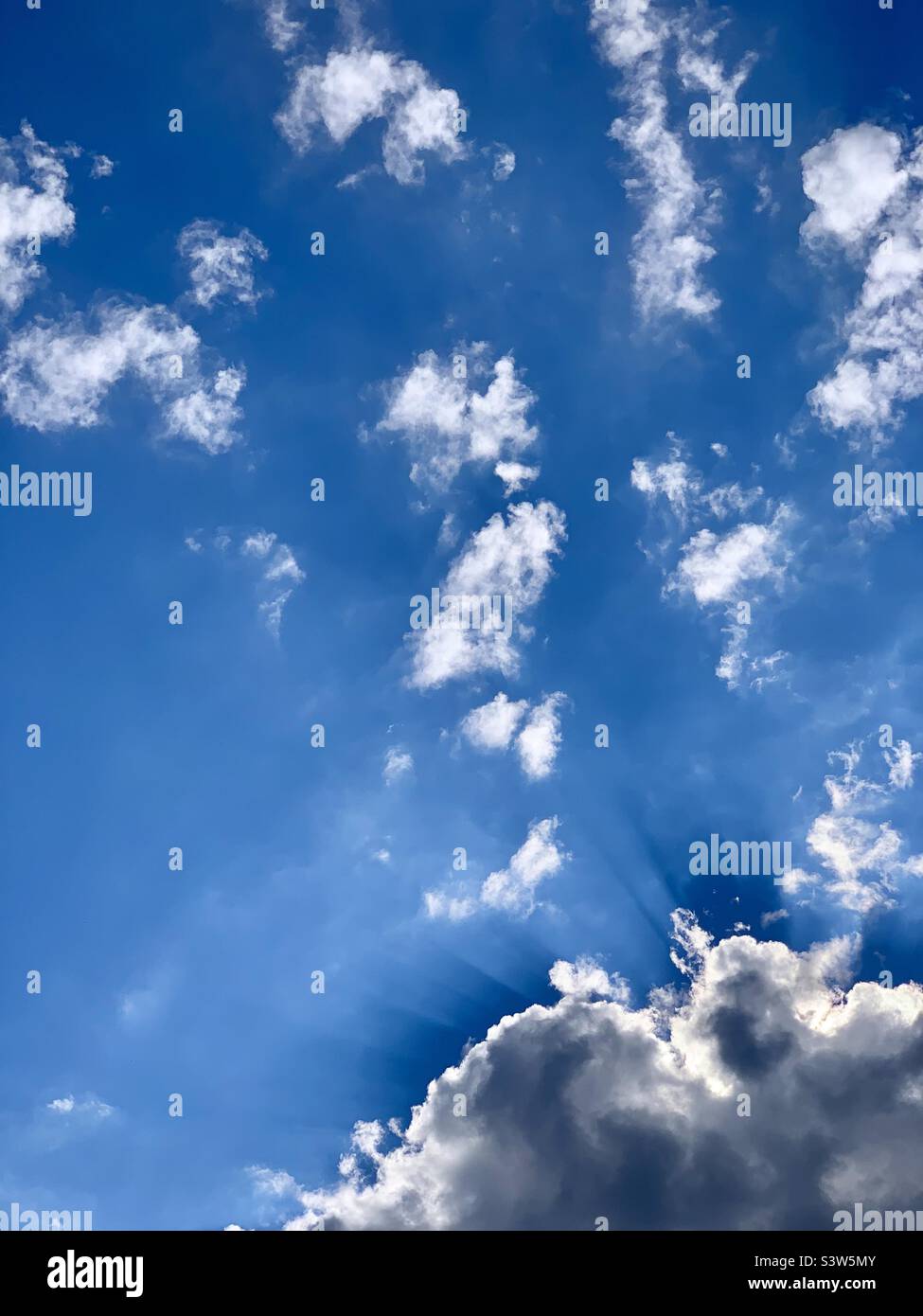 Blue sky with white clouds backlit by sun - Smartphone Captured Stock Image